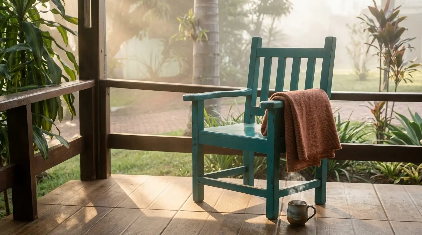 Cadeira de madeira teal na varanda do spa, com manta e caneca fumegante numa manhã de névoa