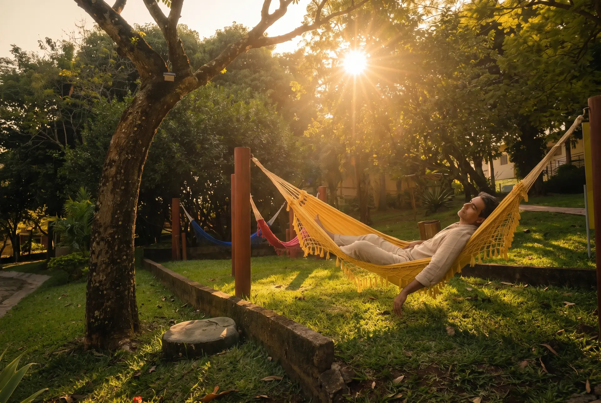 Hóspede descansando de olhos fechados na rede amarela do redário do Água Santa, com o sol de fim de tarde atravessando as árvores